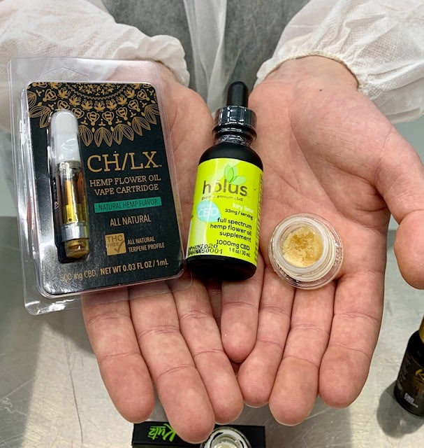CBD vape cartridge, tincture and isolate held in hands