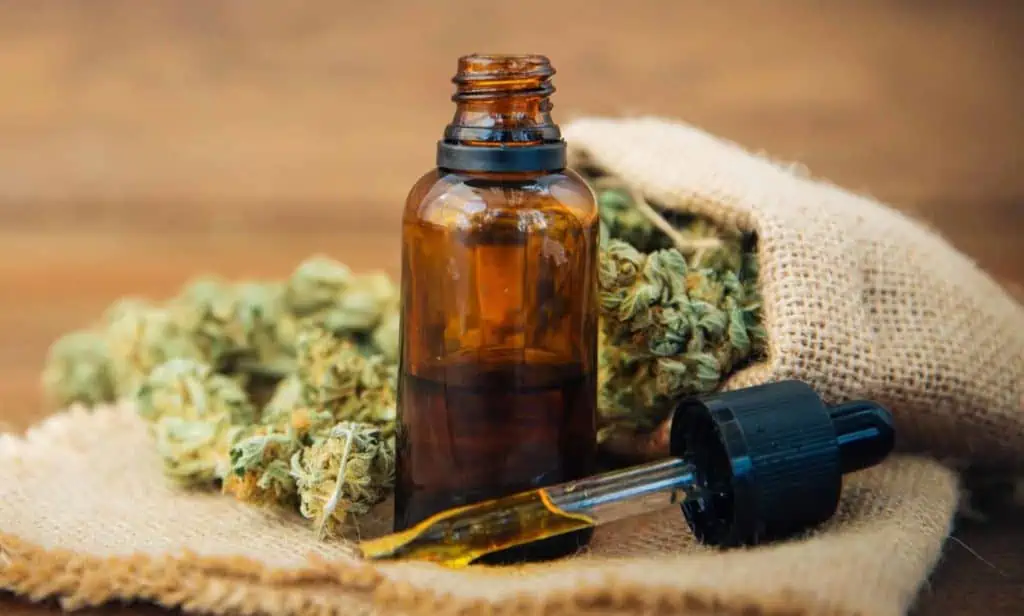 cbd oil in small bottle with hemp at back